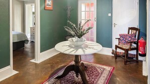 A room with a round table, a chair, a bed, a door, and a fire extinguisher. - 5 bedroom accommodation in Perranporth (Perranporth)