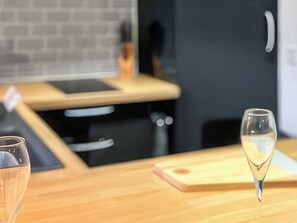 A kitchen with a wooden countertop, a cutting board, and two glasses. - Barn Owl Lodge 1 - UK51444 (Corton)