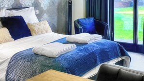 Ein Hotelzimmer mit einem Bett, einem Holztisch und Blick ins Freie.