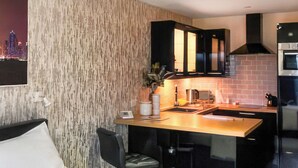 Una cocina moderna con barra, una silla de comedor y una cama con almohada.
