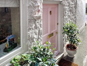 A pink door with a brass knocker, a white textured wall, and a potted plant on the sidewalk. - Berry Cottage - UK51465 (Bishopton, near Ripon)