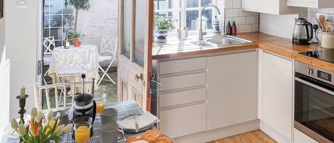 Cozinha compacta com bancada de madeira, pia e forno embutido.