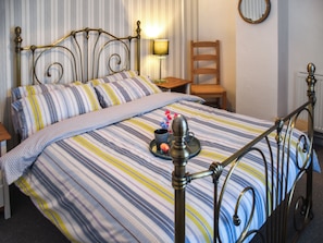 Un lit avec une couvre-lit à rayures, une table de chevet avec une lampe et une chaise.