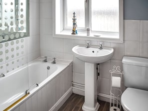 Une salle de bain avec une baignoire, un lavabo, des toilettes et une fenêtre donnant sur un beau paysage.