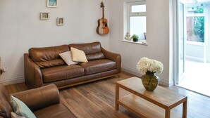 Un salon avec un canapé en cuir marron, une table basse en bois et un vase de fleurs.