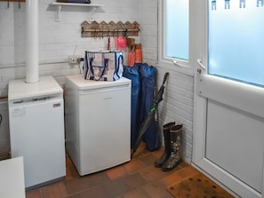 Un espace dédié à la lessive, comprenant un lave-linge, un étendoir et une paire de bottes.
