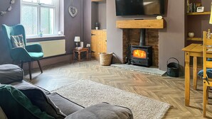 A living room with a fireplace, a television, a sofa, and a chair. - 1 bedroom accommodation in Kelbrook (Kelbrook)