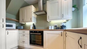 A kitchen with white cabinets, a built-in oven, a microwave, and a coffee machine. - 1 bedroom accommodation in Kelbrook (Kelbrook)