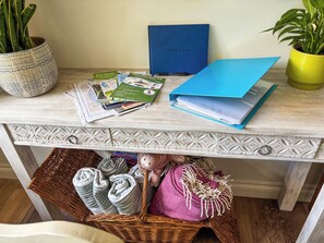 Een bureau met een blauw boek, folders, een kaart en een rieten mand met handdoeken.