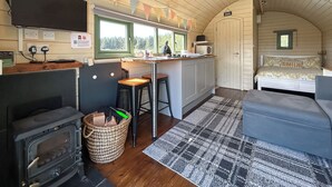 A compact cabin-style room with a kitchenette, a bed, and a large window. - Chesnut Pod - UK51519 (Newton Stewart)