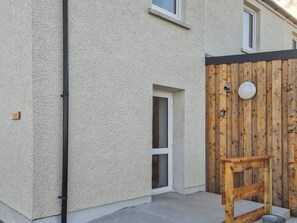 Una casa con fachada texturizada, un portón de madera y una puerta pequeña.