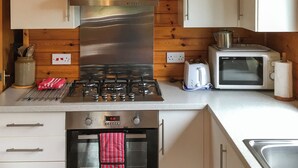 A kitchen with a stainless steel range, a toaster, a microwave, wooden paneling, and a small oven. - The openness of the park and the closeness to the shore. (Acharacle, near Ardnamurchan)