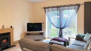 Un salon avec une télévision, un canapé et une cheminée.