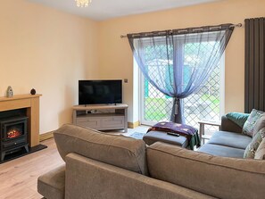 A living room with a television, sofa, and fireplace. - Acorn Cottage - UK51535 (Wilberfoss, near York)