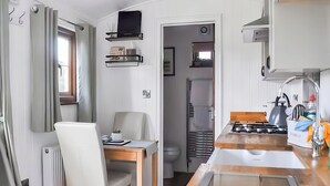 A compact kitchen with a dining area, a built-in stove, and a small refrigerator. - 1 bedroom accommodation in Ilfracombe (Ilfracombe)