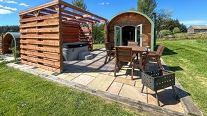 Eine hölzerne Außenanlage mit Whirlpool, Sitzbereich und überdachter Terrasse.