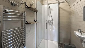 Eine Dusche mit Glastür, einem Handtuchhalter und einem Waschbecken.