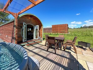 A wooden cabin with a patio, a hot tub, and a view of a field. - Spruce Pod - UK51539 (Newton Stewart)