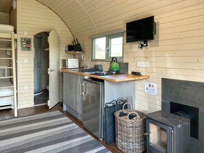 A compact kitchen with a stove, microwave, and a green kettle. - Spruce Pod - UK51539 (Newton Stewart)
