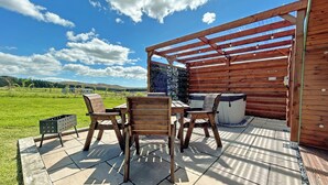 An outdoor patio with wooden furniture, a hot tub, and a pergola. - 1 bedroom accommodation in Newton Stewart (Newton Stewart)