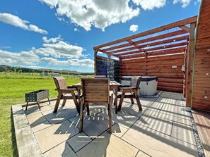 An outdoor patio with wooden furniture, a hot tub, and a pergola. - 1 bedroom accommodation in Newton Stewart (Newton Stewart)