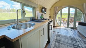 A kitchen with a sink, stove, and a view of the outdoors through a window. - 1 bedroom accommodation in Newton Stewart (Newton Stewart)