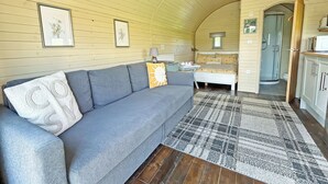 A cozy interior with a sofa, a patterned rug, and a bed with floral bedding. - 1 bedroom accommodation in Newton Stewart (Newton Stewart)