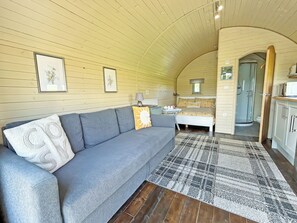 A cozy interior with a sofa, a patterned rug, and a bed with floral bedding. - 1 bedroom accommodation in Newton Stewart (Newton Stewart)