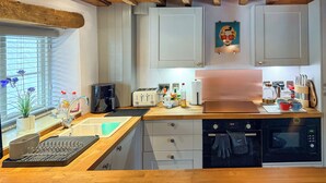 A modern kitchen with wooden beams, white cabinets, a coffee maker, a toaster, and a microwave. - 1 bedroom accommodation in Blunsdon (Blunsdon)