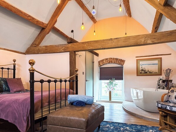 A bedroom with a four-poster bed, a wooden bench, a white bathtub, and a painting on the wall. - 1 bedroom accommodation in Blunsdon (Blunsdon)