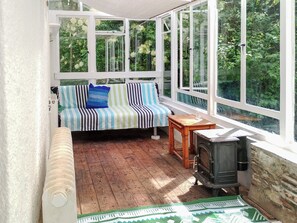Ein gemütliches Zimmer mit Holzboden, einem gestreiften Sofa, einem kleinen Tisch und einem Kaminofen.