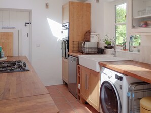 A compact kitchen with a gas stove, a washing machine, and a sink. - 3 bedroom accommodation in Kingsbrisge (Kingsbrisge)