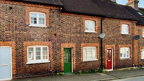 Een rij bakstenen huizen met veel ramen en deuren, waarvan sommige voorzien zijn van luiken, en schotels op de daken.