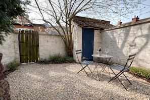 A gravel patio with a table and chairs, a blue door, and a tree. - 1 bedroom accommodation in All Surrey (All Surrey)