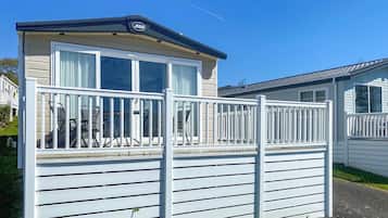 A mobile home with a balcony, a small porch, and a garage.
