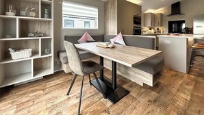 Moderni keittiö, jossa on ruokailutila, puulattia ja sisäänrakennetut hyllyt.