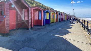 Una hilera de cabañas de playa coloridas a lo largo de un paseo marítimo, bajo un cielo despejado.