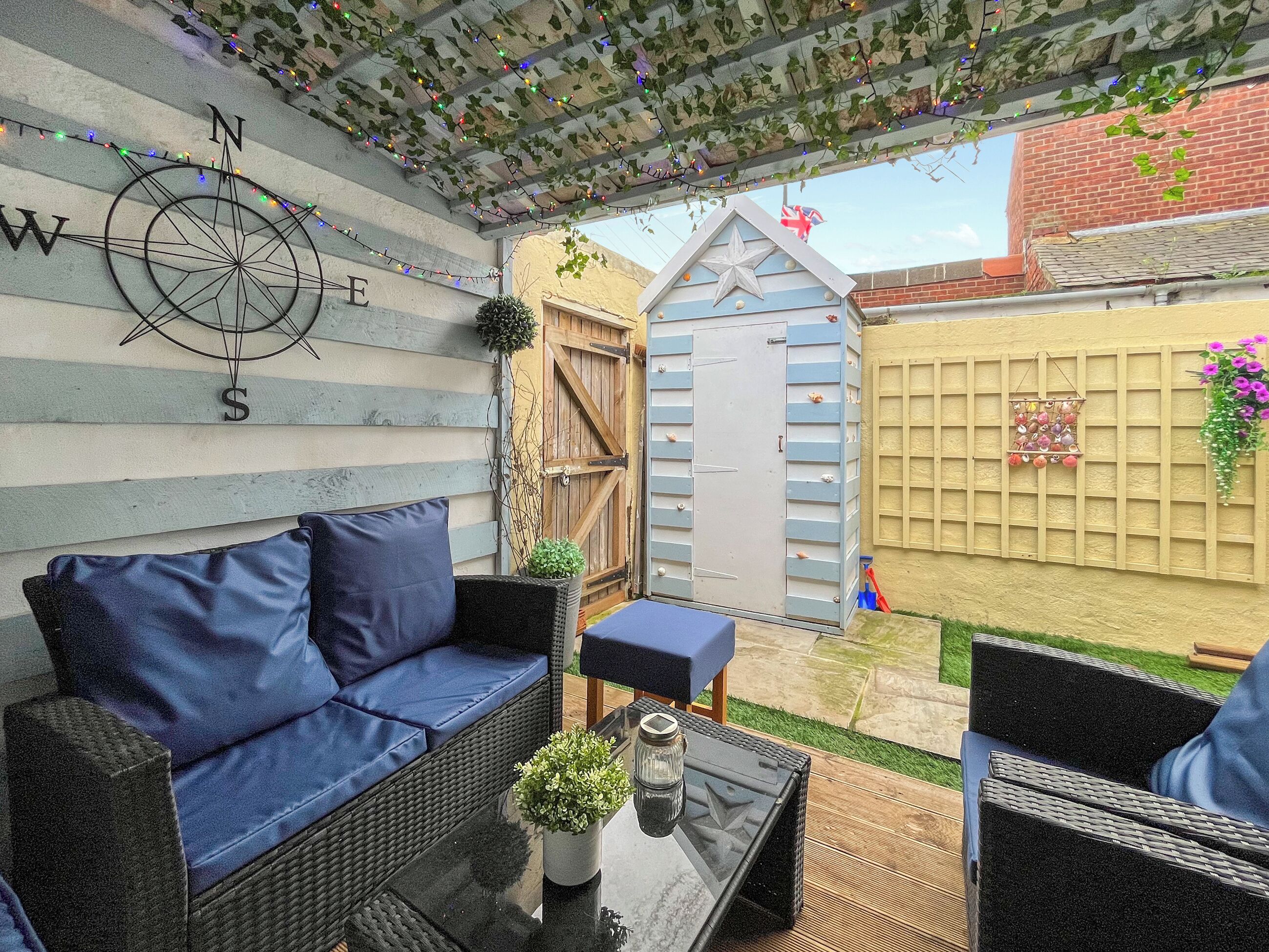 A patio with a blue sofa, a small table, and a potted plant.