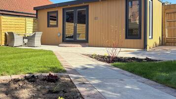 A modern building with a wooden exterior, a patio with outdoor furniture, and a well-maintained garden.