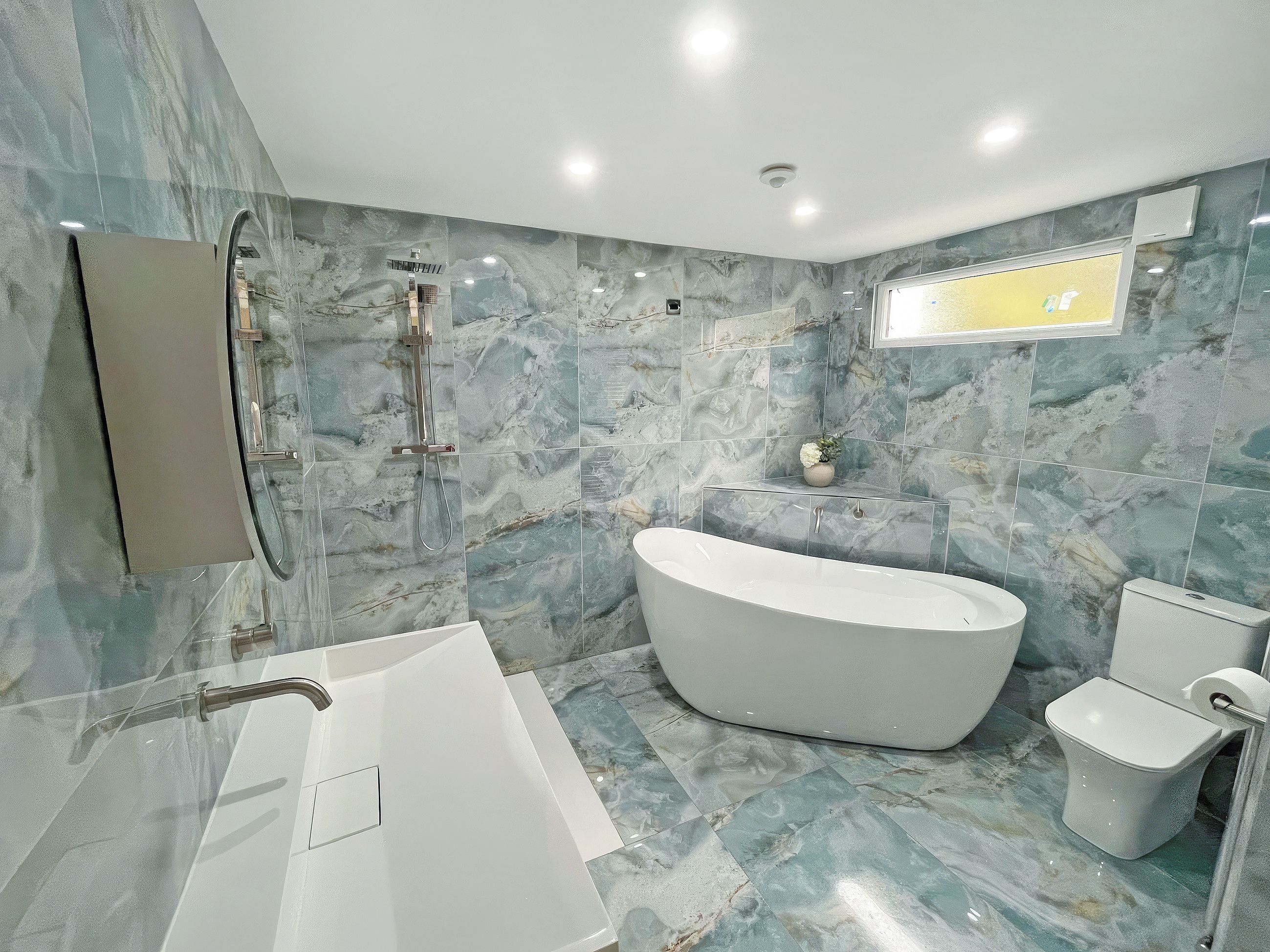 A modern bathroom with a freestanding bathtub, a wall-mounted mirror, and a toilet.