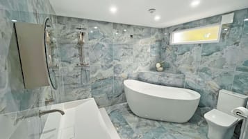 A modern bathroom with a freestanding bathtub, a wall-mounted mirror, and a toilet.