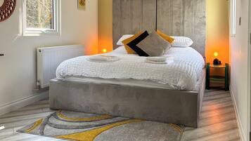 A bedroom with a bed, bedside table, radiator, and a window.