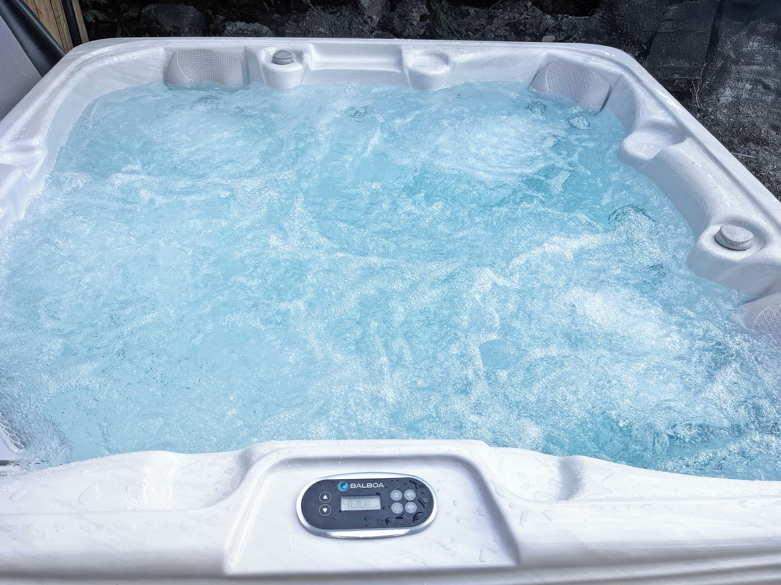 Een hottub met bedieningspaneel, gelegen in een rotsachtig landschap.
