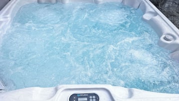 Een hottub met bedieningspaneel, gelegen in een rotsachtig landschap.