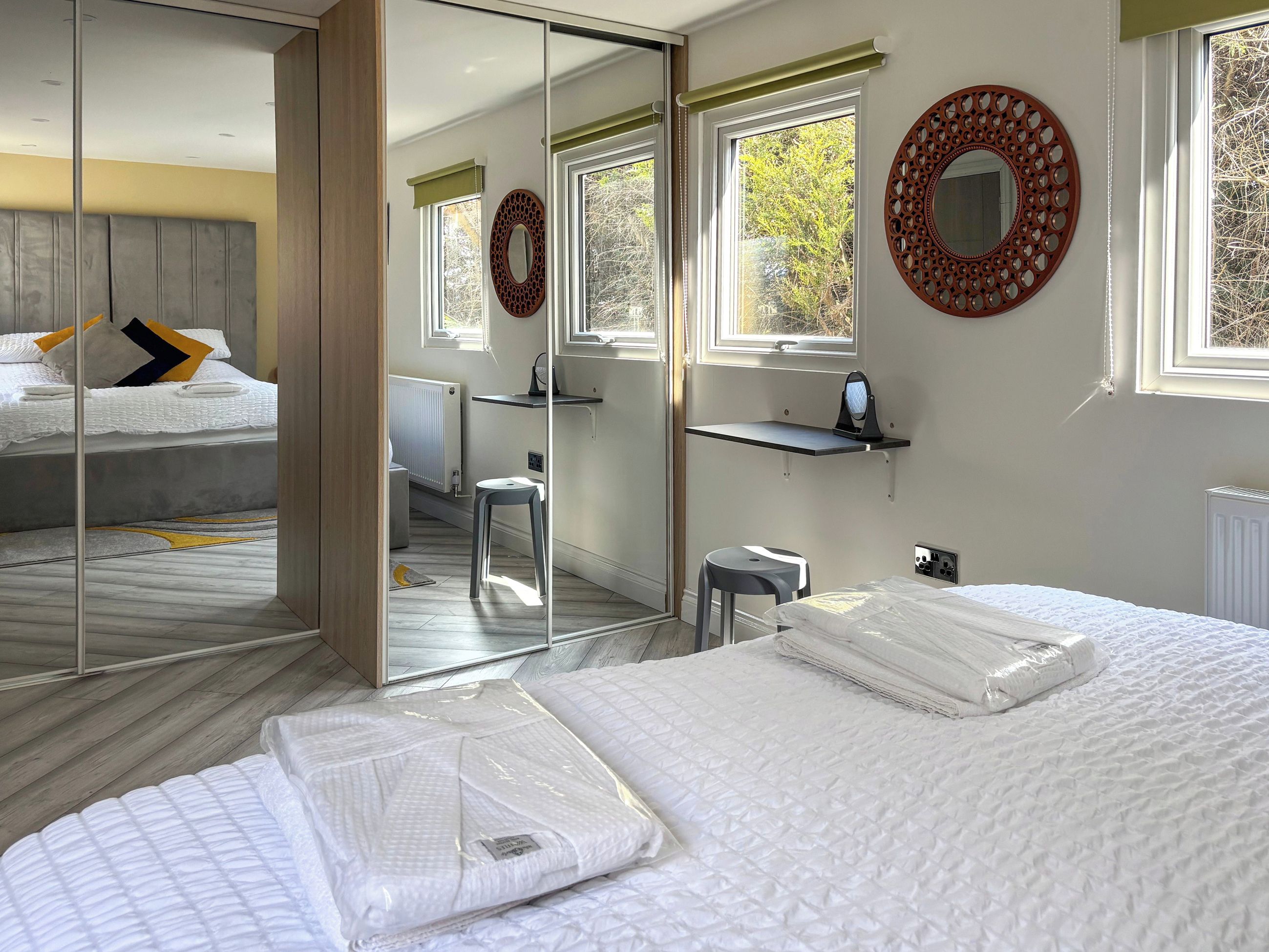 A bedroom with a bed, a desk, a chair, a mirror, and a radiator.
