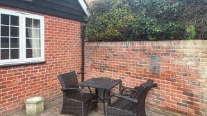 Een terras met een bakstenen muur, een raam en rieten meubels.