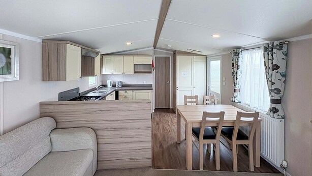 Ett kompakt bostadsutrymme med ett litet kök, en matplats och en soffa.