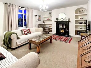 Una sala de estar con sofá, mesa de centro, chimenea y elementos decorativos.