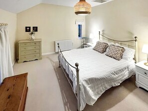 Un dormitorio con cama, cómoda, mesita de noche, lámpara y una lámpara colgante.