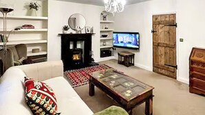 Un salon avec une cheminée, un téléviseur, un canapé et un meuble en bois.